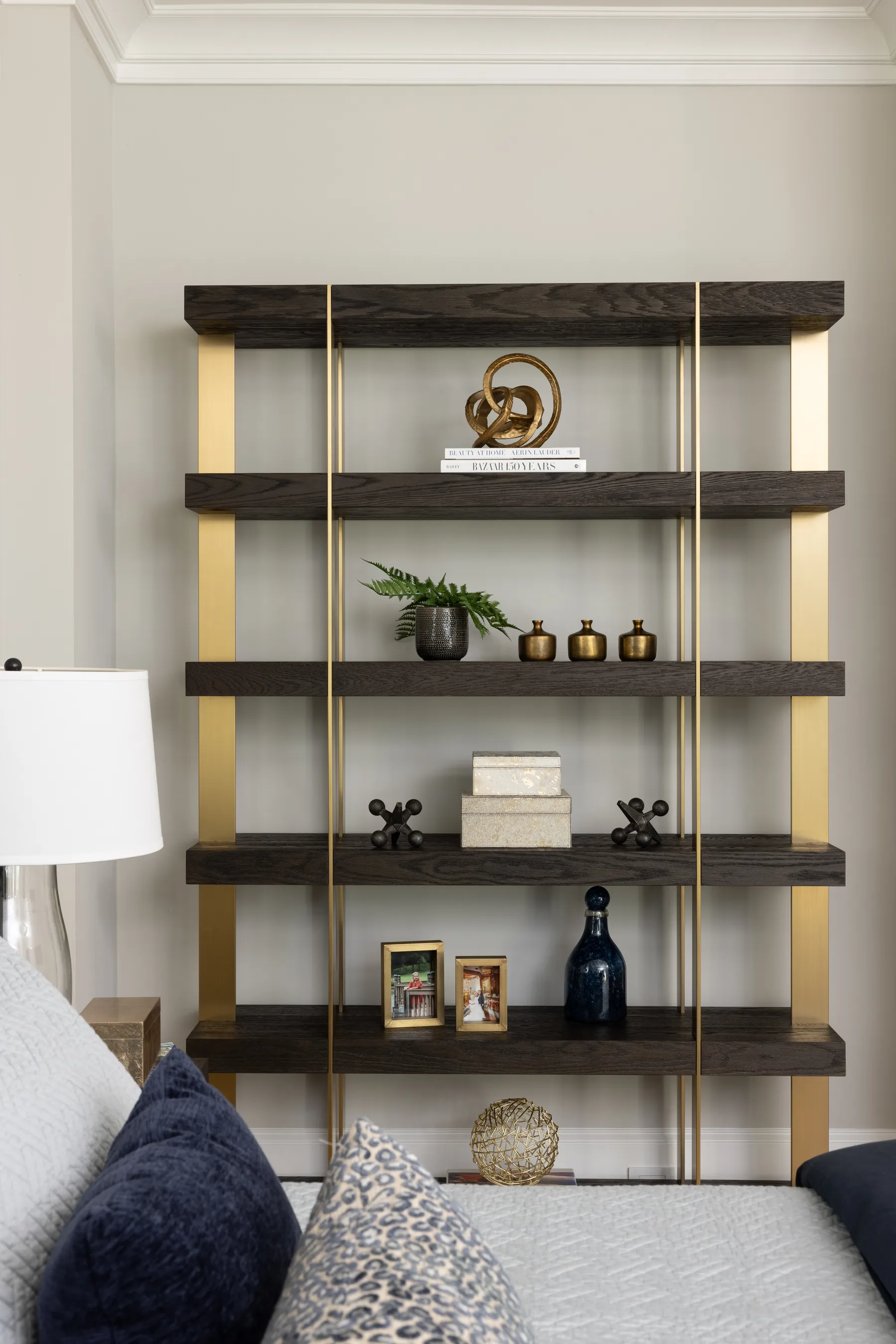 Bronze and wood shelving styled with brass and blue glass.