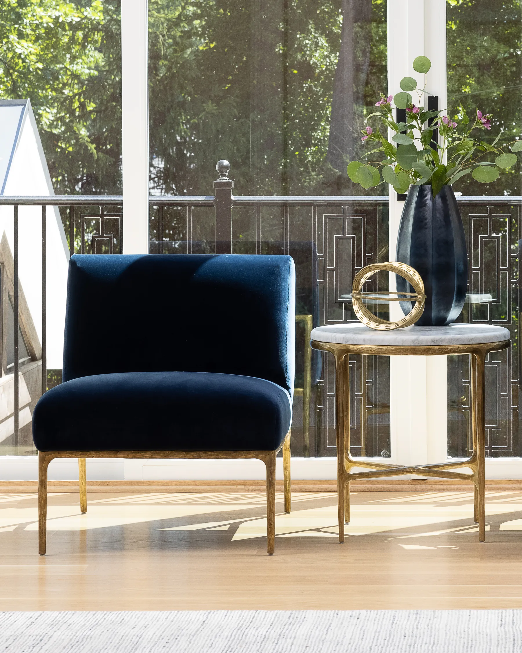 A navy velvet chair and a marble side table in the bedroom sitting area.