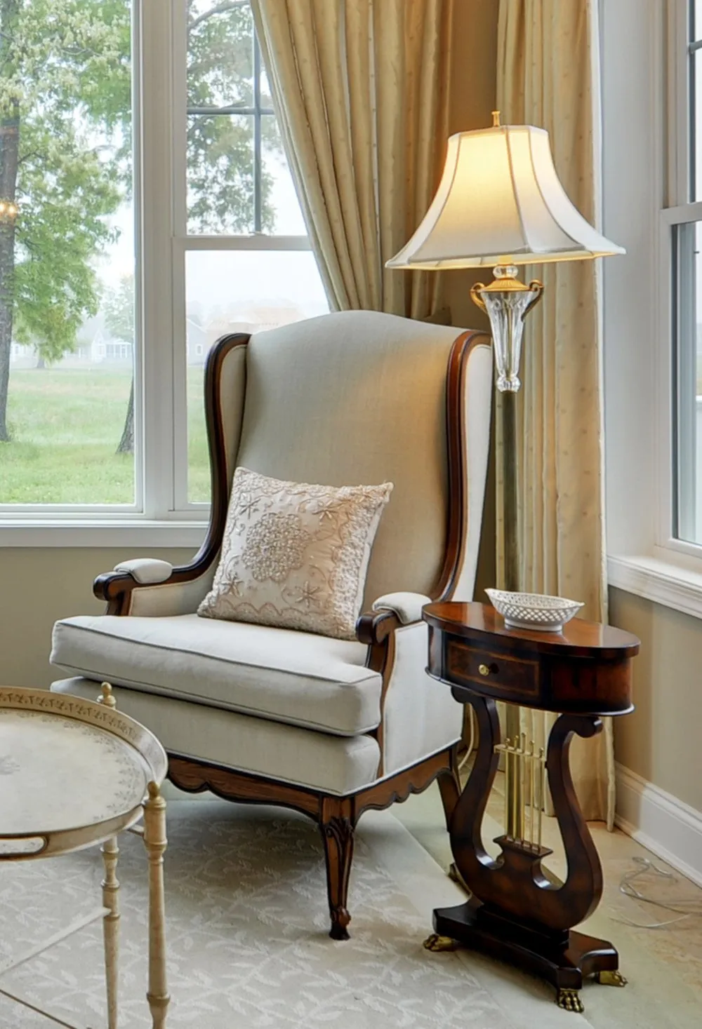 A wing chair and a lyre side table by the window.