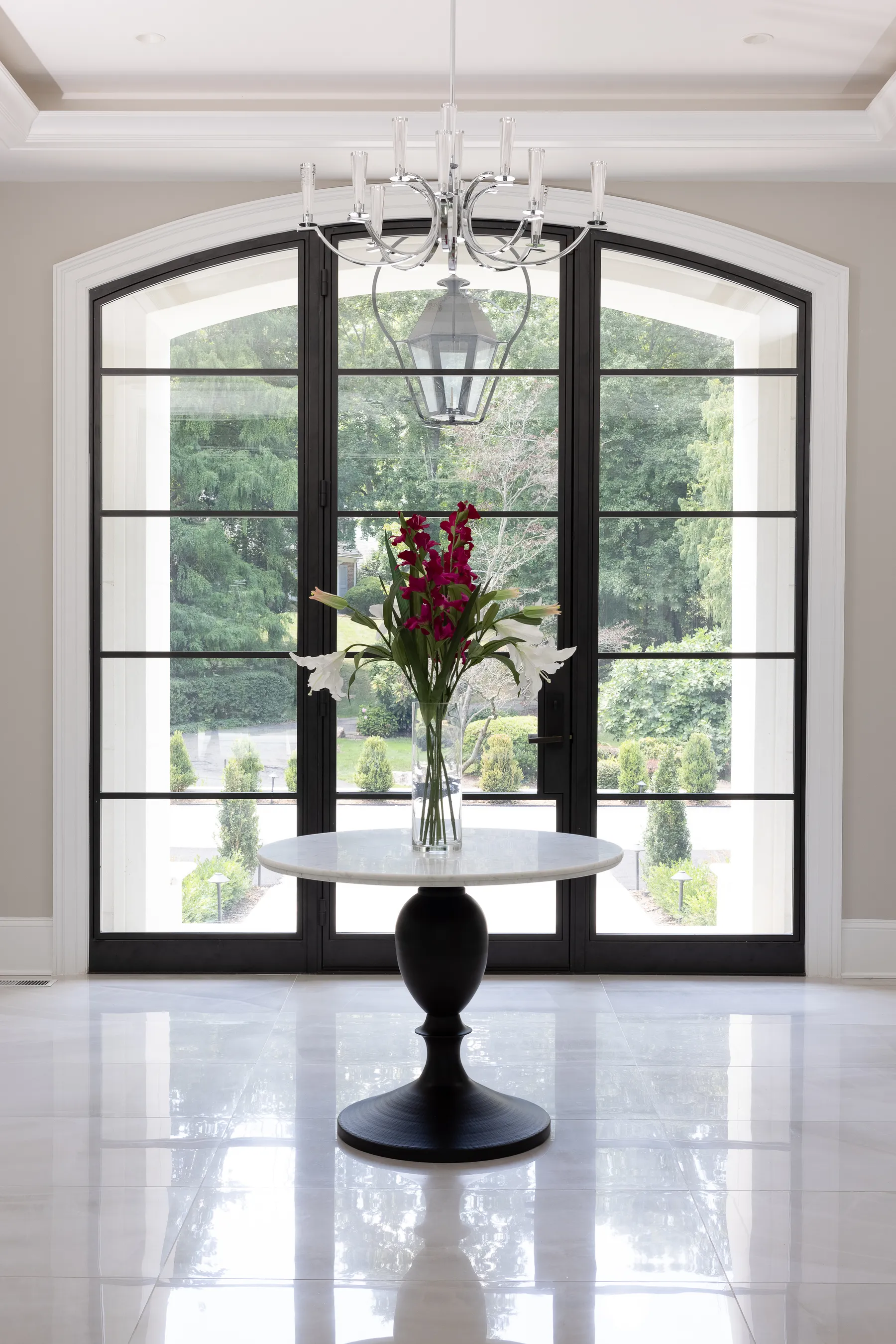 The entry: arched steel doors, a pedestal table and a lantern overhead.