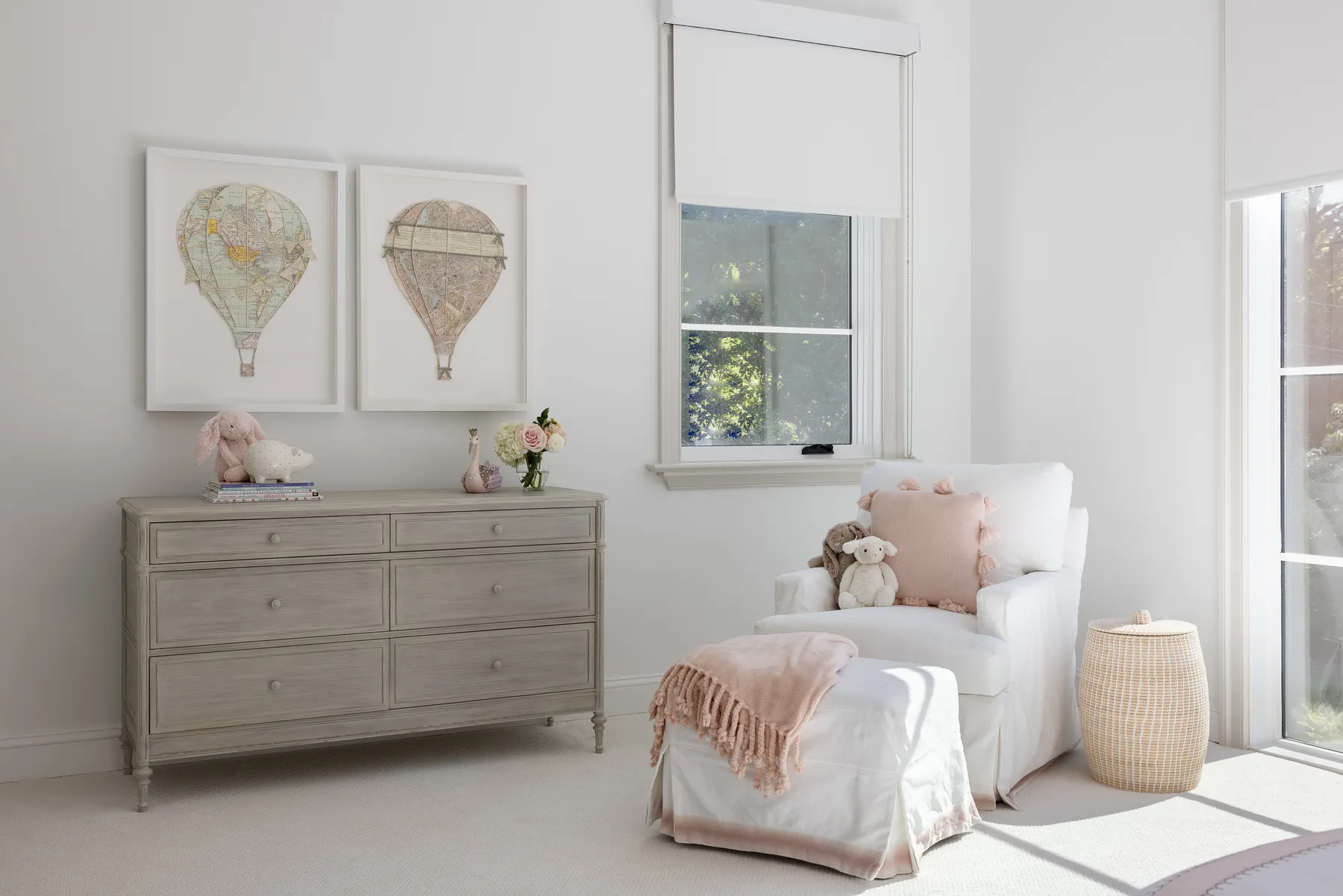 A soft white chair and hot air balloon prints in the nursery.