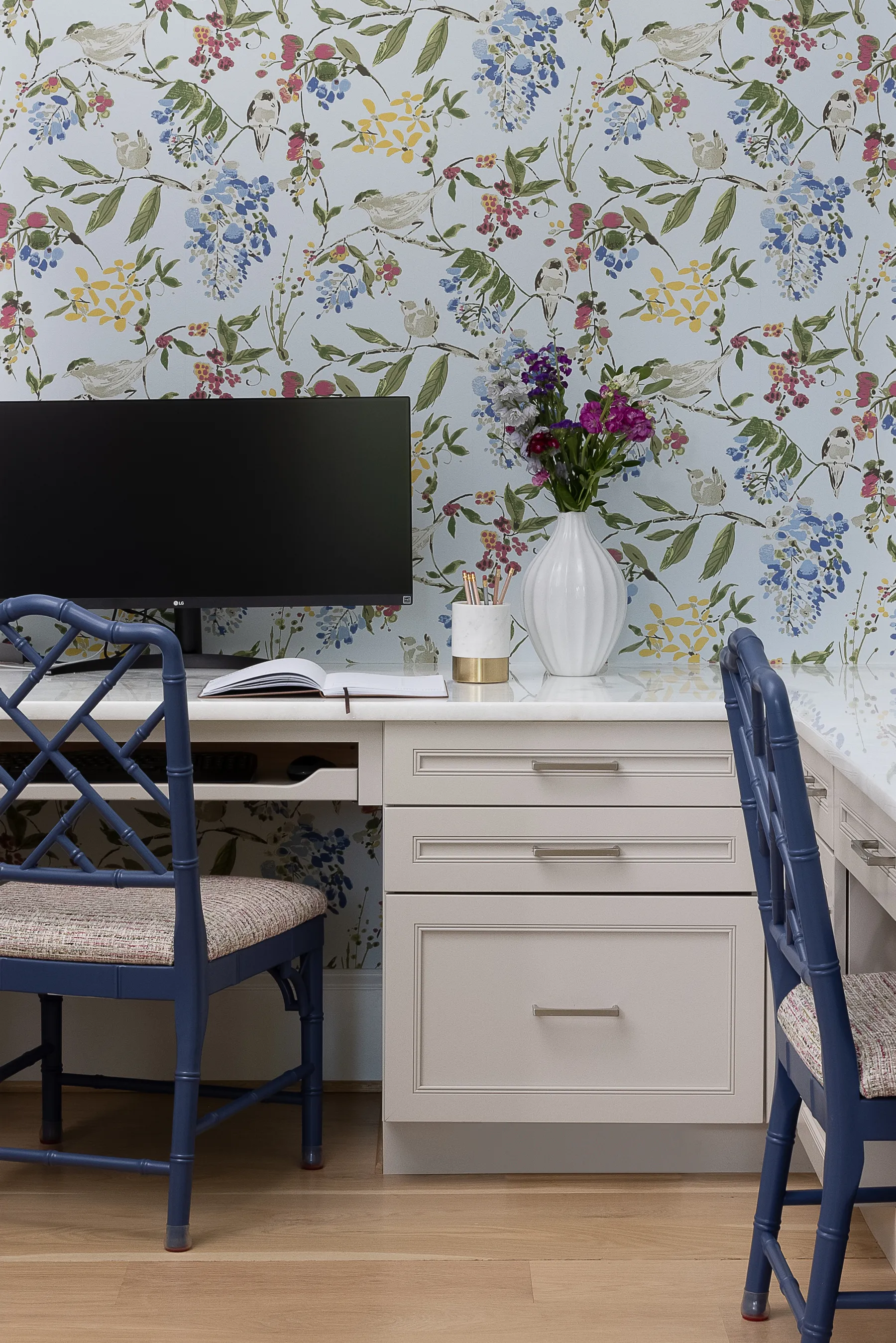 Her office: botanical wallpaper, a white desk and blue lacquered chairs.