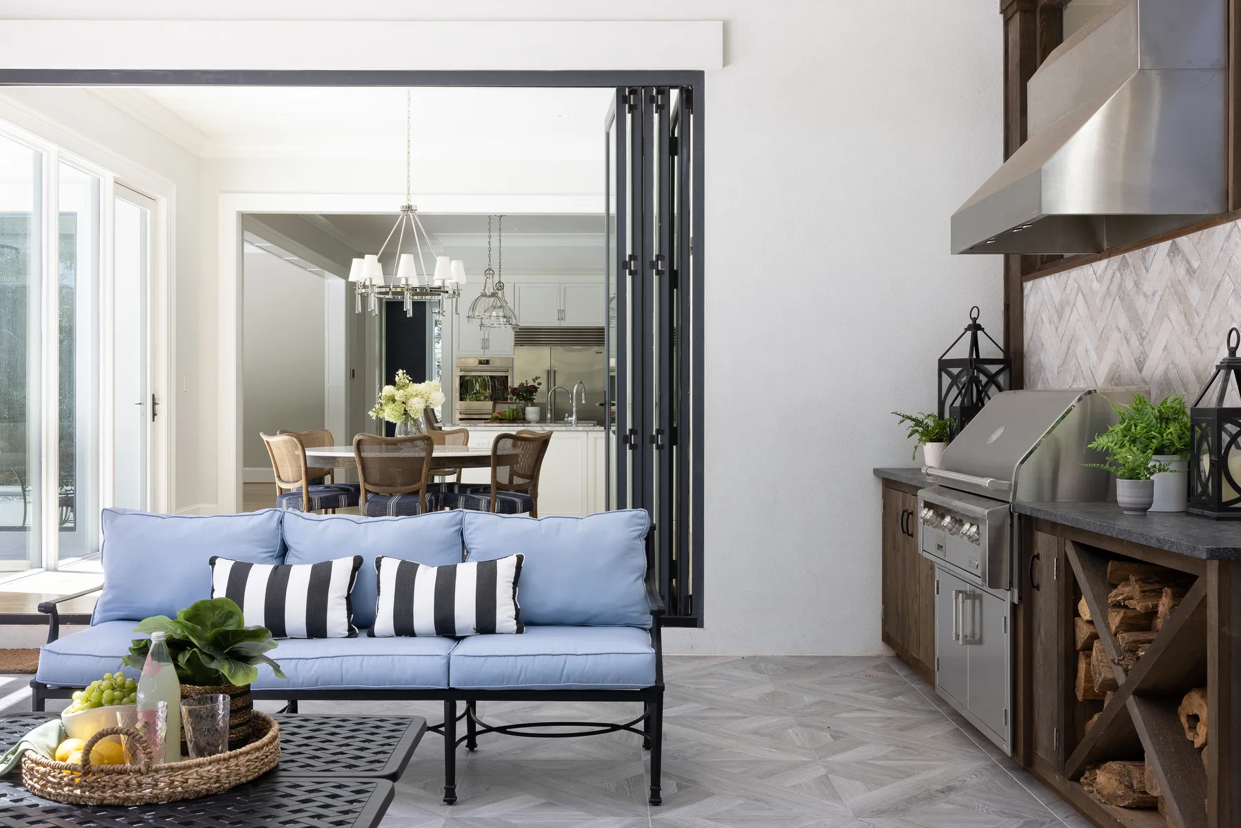 The outdoor room: blue cushions, a grill and serving counter and stacked firewood.