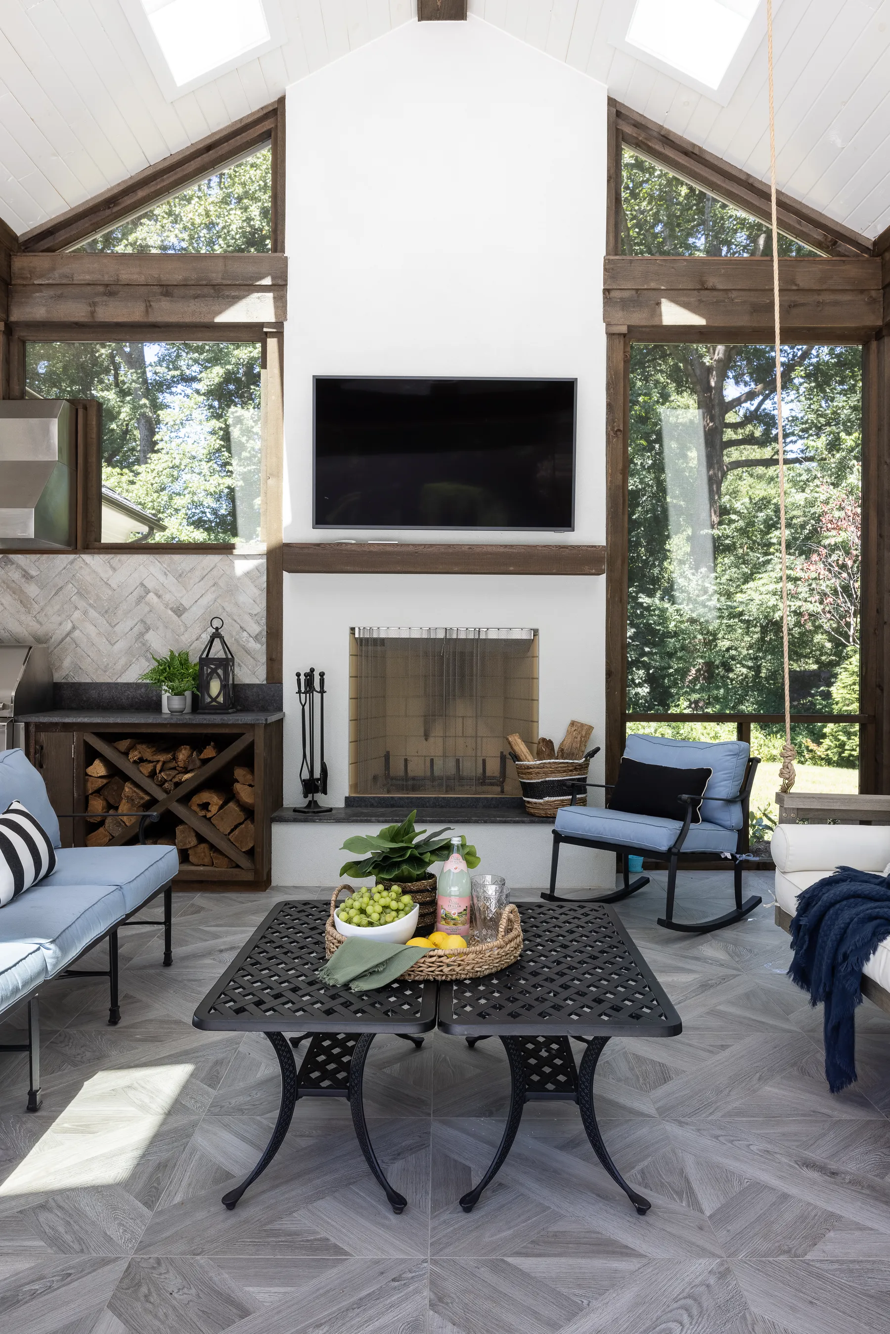 The screened porch with a stone fireplace and a wall of windows.