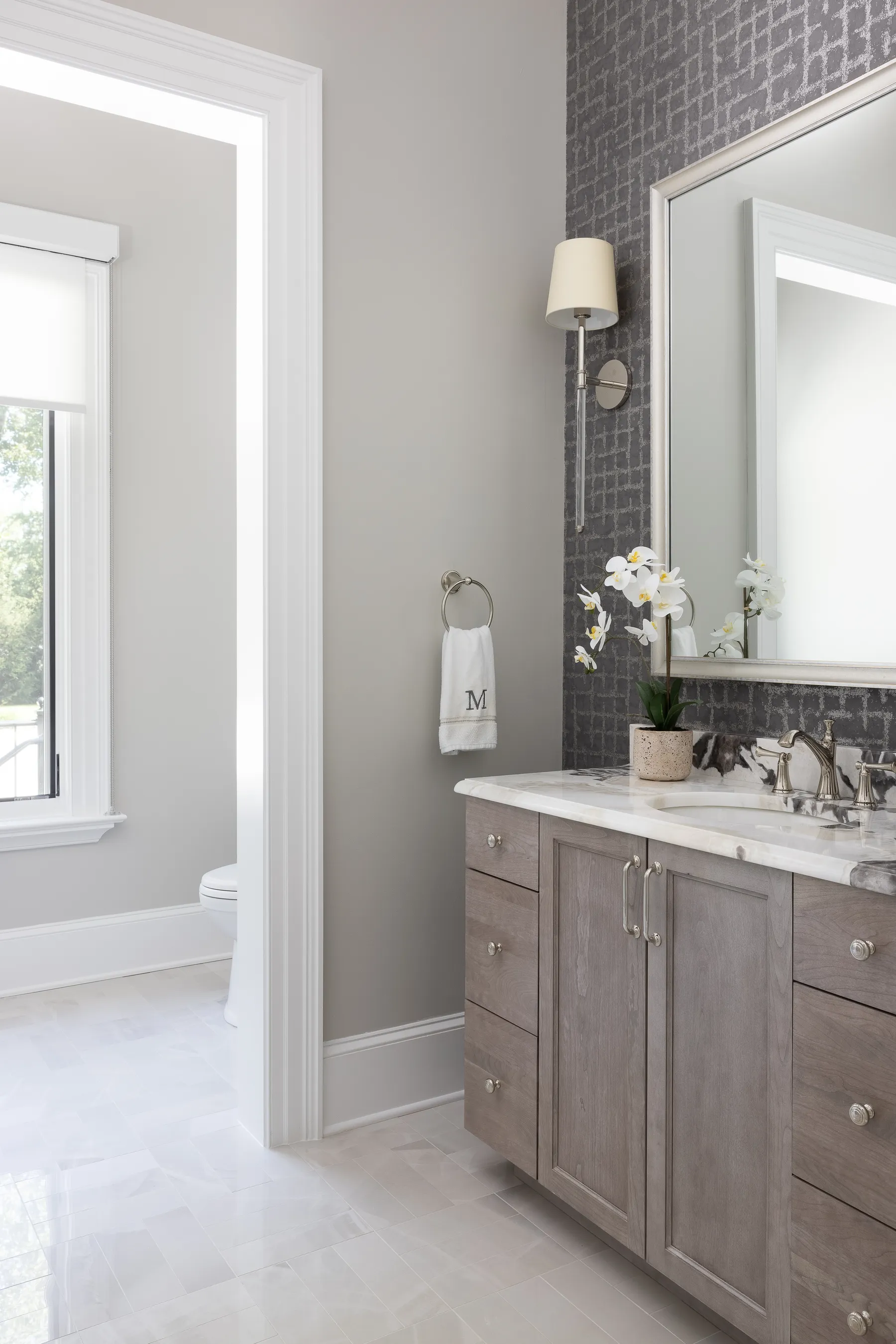 The powder room: a gray vanity, marble top and a single sconce.