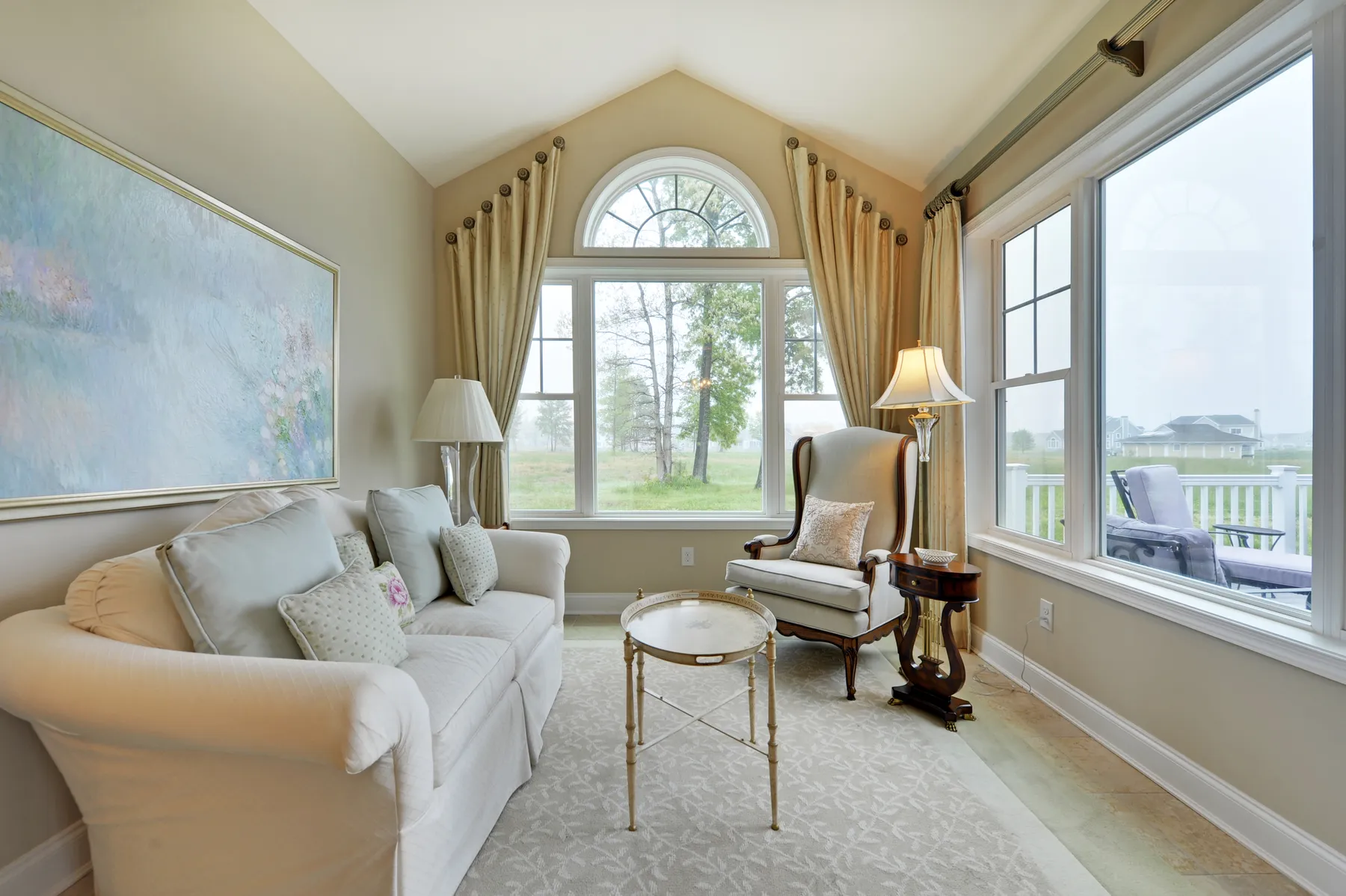 A sunroom under an arched window, in ivory and soft blue.